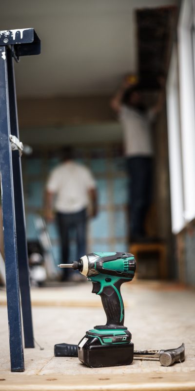 Battery Drill on the Floor with Worker in Background